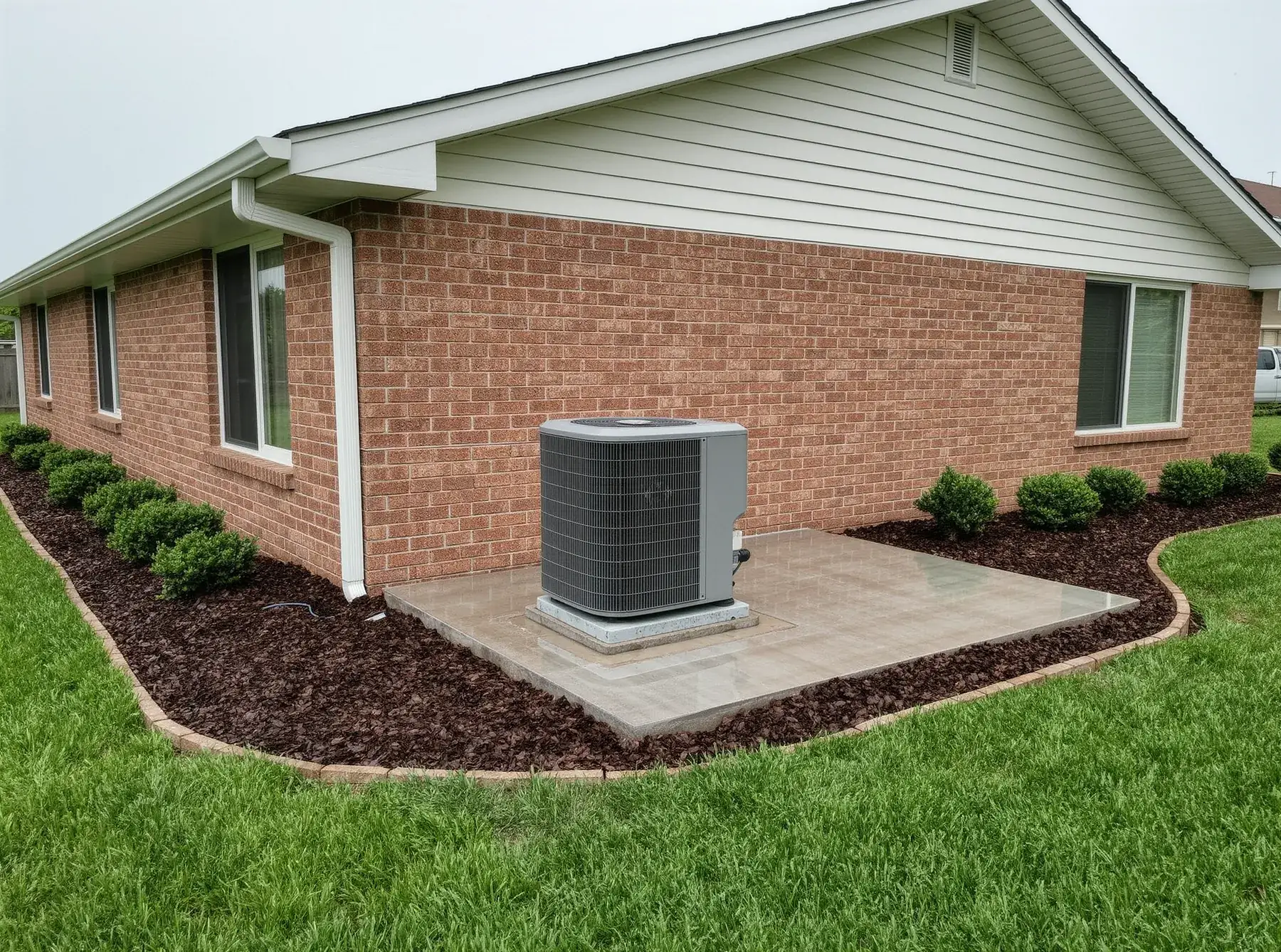 A new heat pump outdoor unit on a concrete pad beside a brick ranch home