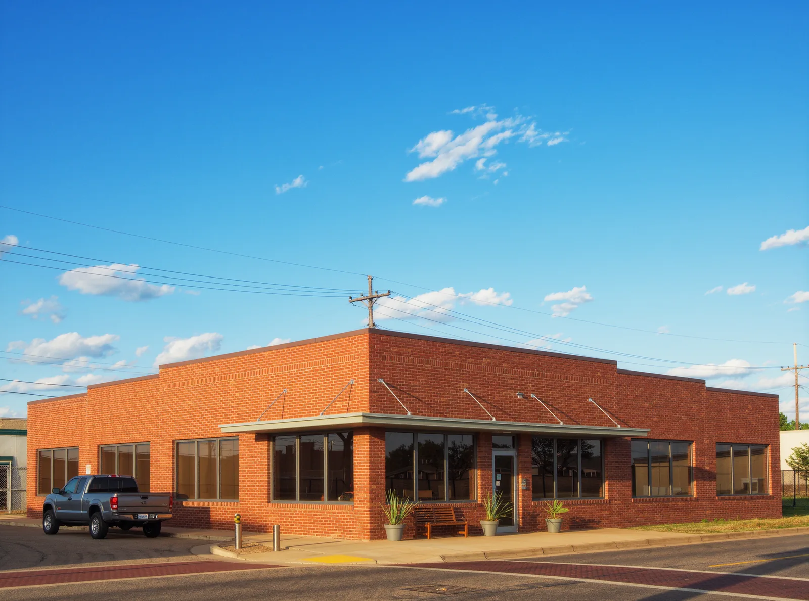 A single story red brick office building in Fort Worth under a wide blue sky, with a pickup truck parked at the curb